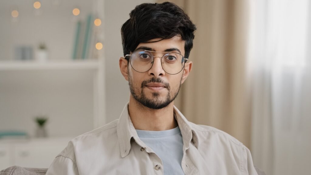 Calm portrait close-up bearded face millennial arabic indian man guy with glasses looking at camera